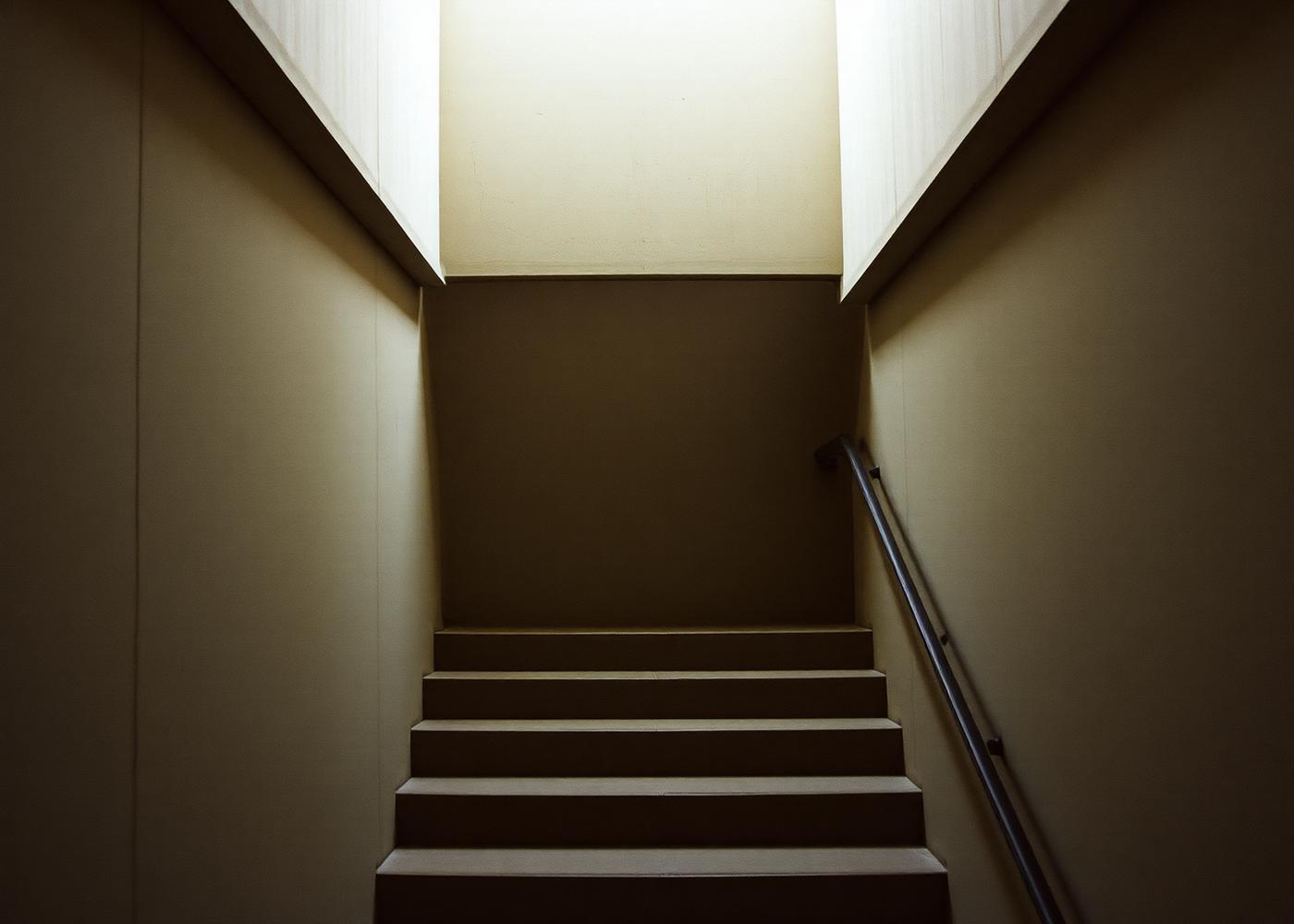 A concrete stairwell lit by a hard diagonal shaft of light